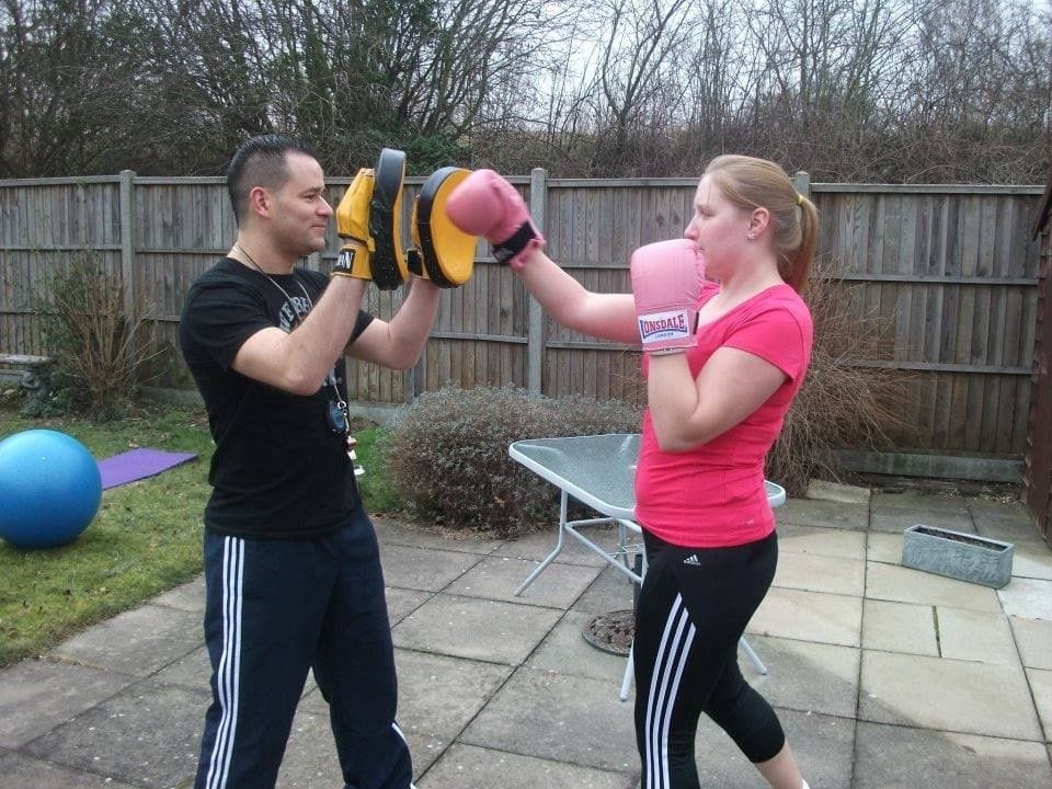 Peter, a PMA personal trainer, guiding a client through a personalised exercise routine in a comfortable home gym setting